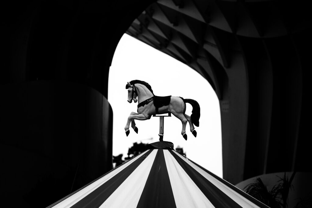 Black and white photo off a wooden horse on top of a merry-go-round