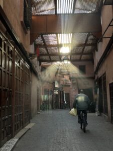 small alleyway with a man on a bicycle and sunrays